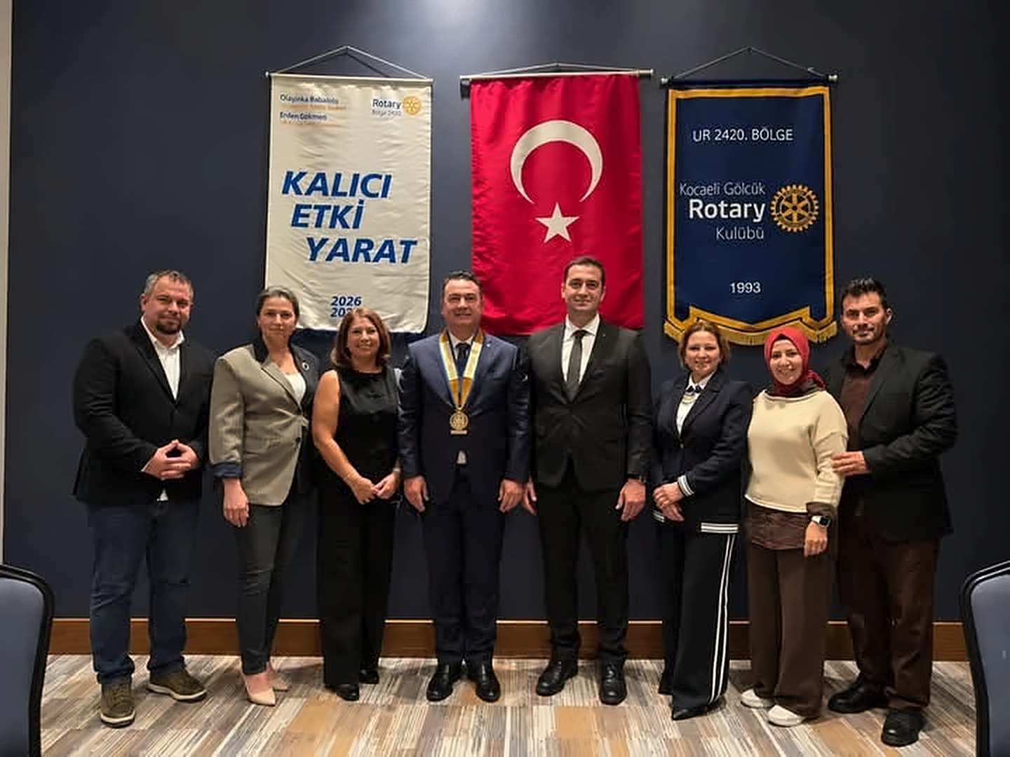 Kulüp üyeleri Rotary bayrakları ve kulüp flaması önünde